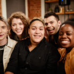 group of young cheerful friends posing for selfie in front of camera