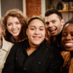 group of young cheerful friends posing for selfie in front of camera